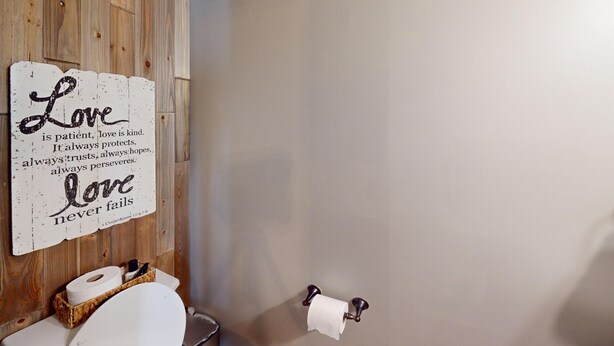 A bathroom with a wooden wall, a toilet, and a roll of toilet paper on the wall. - 2196 Major Loring Way SW, Marietta (Marietta)