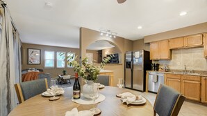 A dining area with a wooden table set for four, a vase with flowers, and a bottle of wine. - 3754 Red Canon (Colorado Springs)