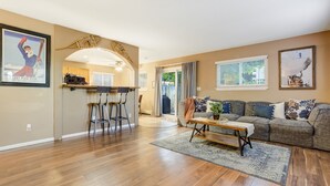 A spacious living area with a wooden floor, a sofa set, and a kitchen area with bar stools. - 3754 Red Canon (Colorado Springs)