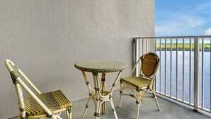En balkon med to fletstole og et lille bord, med udsigt over vandet.