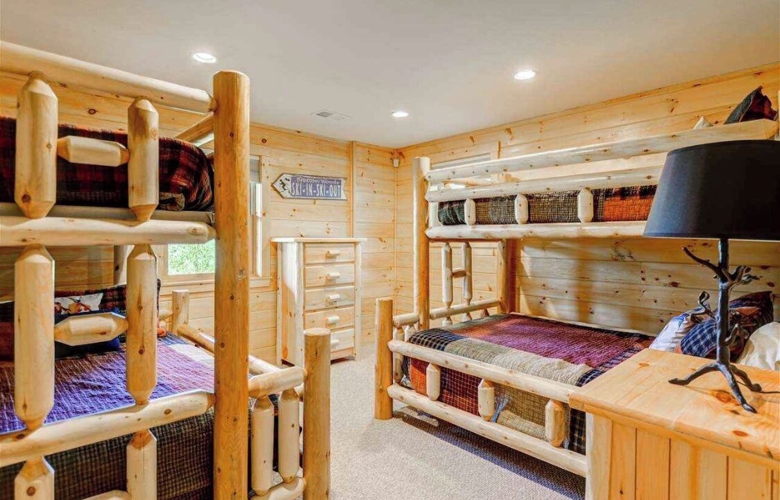 Una cabaña de madera con literas, un aparador y un letrero que indica acceso directo a las pistas.