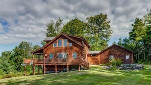 A two-story log cabin with a balcony and a smaller attached structure. - 489oer (Whitefield)