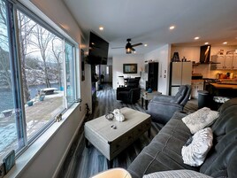 Una sala de estar moderna con un sofá gris, una mesa de centro y vistas a un río.