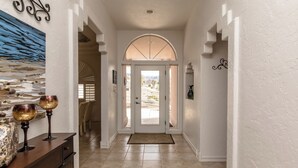 Un couloir avec une porte blanche, une arche décorative et une vue sur l’extérieur.