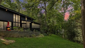 A modern house with a stone fireplace, large windows, and a well-maintained lawn. - Pineview Haven (Knoxville)