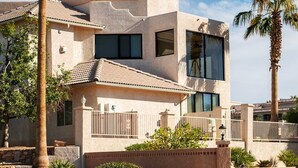 Une maison moderne à deux étages, avec une façade en stuc, de grandes fenêtres et un balcon.