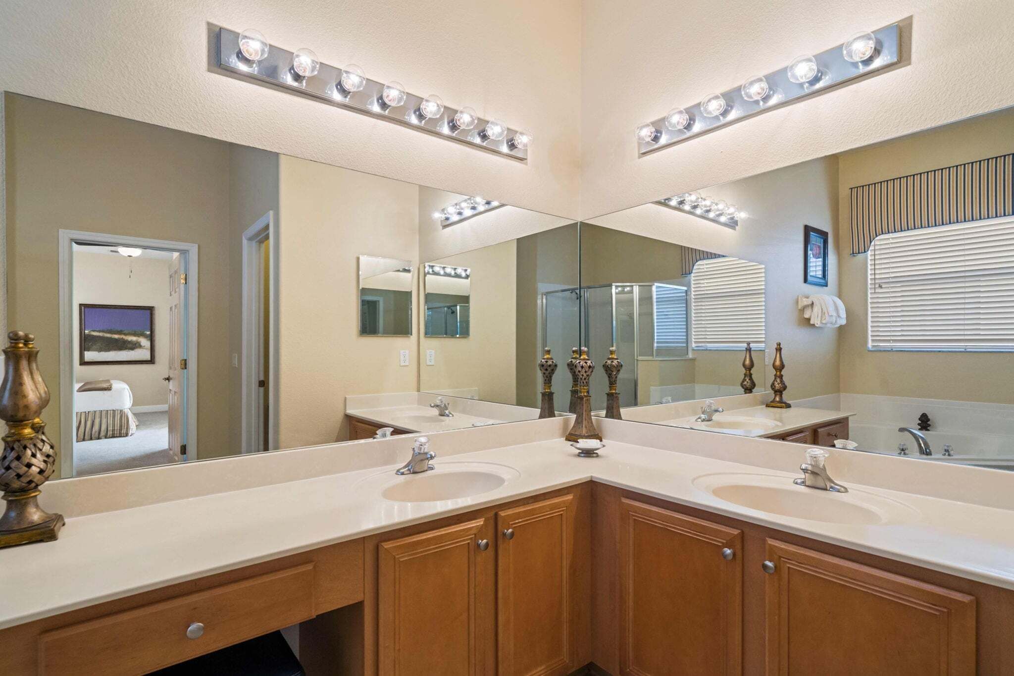 Une salle de bain avec deux lavabos, un grand miroir, des meubles de salle de bain et un lampadaire.