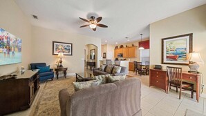 A spacious living area with a ceiling fan, a dining table, and a kitchen in the background. - Os404y Homestead Foxglove (Kissimmee)