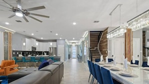 A modern kitchen with white cabinets, a central island, and blue bar stools. - Top Luxury Villa Storey Lake Mins to Disney (Kissimmee)