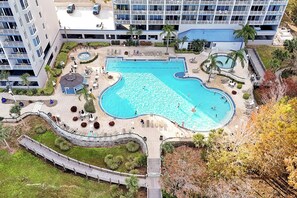 Ein Luftbild eines Hotels mit großem Schwimmbecken, Liegebereichen und einer überdachten Terrasse.