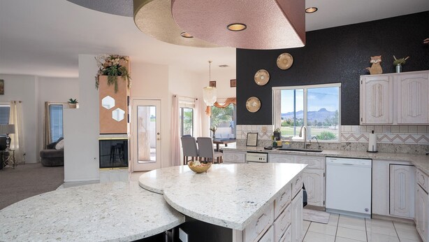 Una cocina moderna con armarios blancos, una isla grande y vistas al exterior.