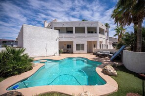 Une maison moderne dotée d’une piscine, d’un espace salon extérieur et de palmiers.