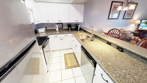 A kitchen with white cabinets, a stainless steel sink, a toaster, and a coffee maker. - Village at the Glens C 204 (Little River)