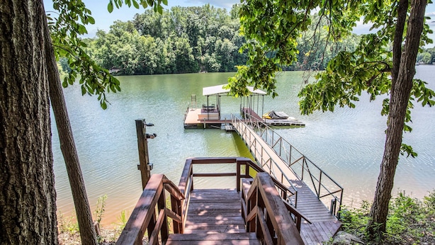 A wooden dock leading to a small boat on a calm lake, surrounded by trees. - Dogwood Cabin (Martin)