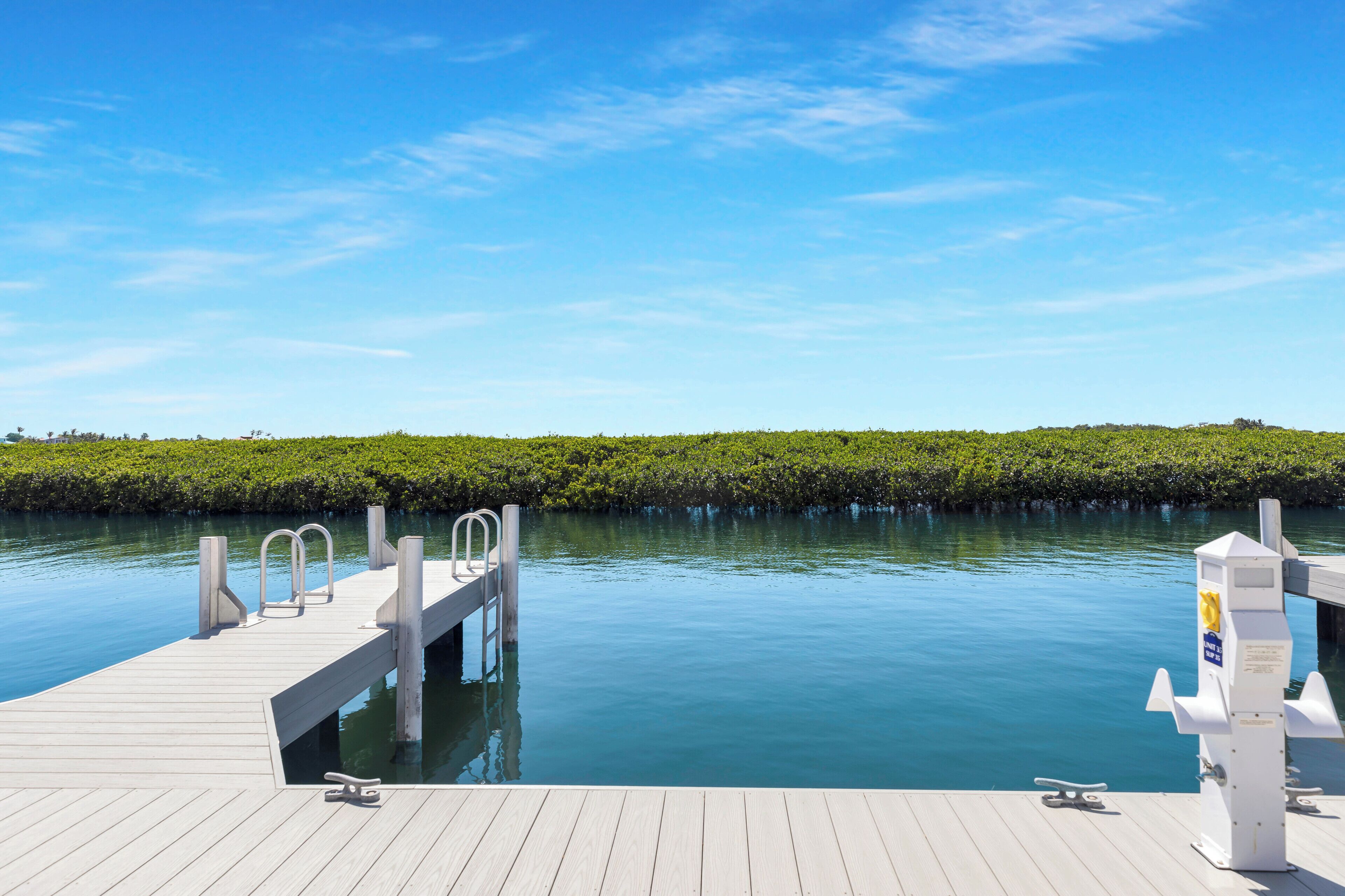 A wooden dock extending into calm water with a clear sky above.