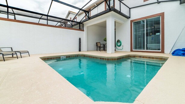 A swimming pool with a glass ceiling, a chair, and a table. - Jlt3076 Storey Lake Resort Vacation Townhome (Kissimmee)