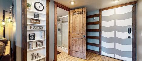 Un couloir avec une porte en bois, une douche en verre et un mur orné de citations inspirantes.