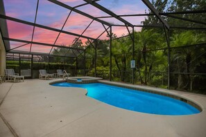 Un espace piscine doté d’une zone abritée, de chaises longues et offrant une vue sur les arbres.