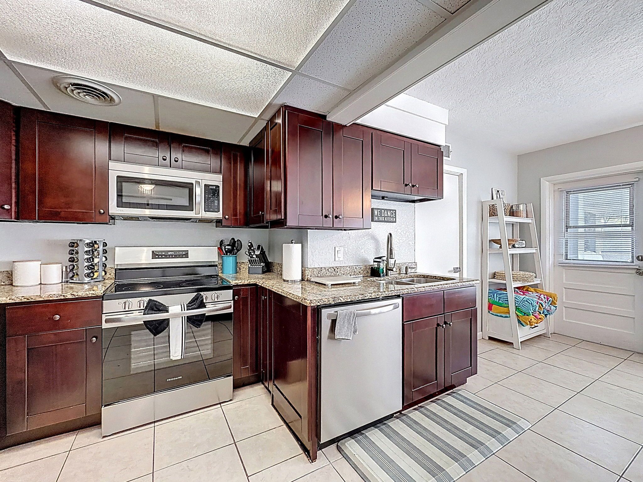 A modern kitchen with dark wood cabinets, stainless steel appliances, and a granite countertop.