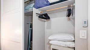 A bedroom with a bed, a radiator, and a closet with hanging clothes. - Maalaea Banyans 411 (Wailuku)
