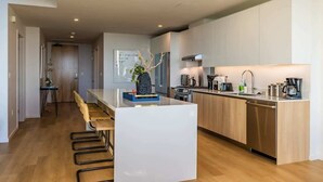 A modern kitchen with a central island, stainless steel appliances, and a wooden dining area. - @ Marbella Lane - Luxurious 3BR Penthouse (Long Beach)