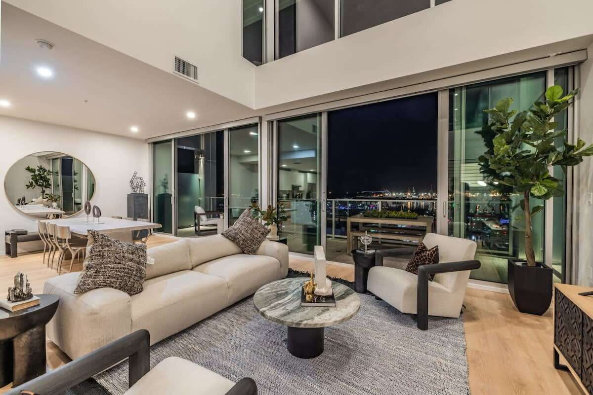 A modern living room with a sofa, armchairs, a coffee table, and a dining area with a table and chairs.