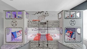 Ein Zimmer mit Etagenbetten, Wandgemälde und mehreren Fenstern.