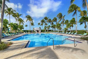 Une piscine avec des chaises longues et des palmiers.