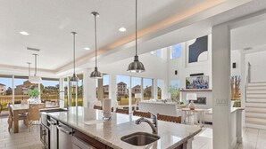 Una cocina amplia con una isla grande, iluminación colgante y vistas al vecindario.