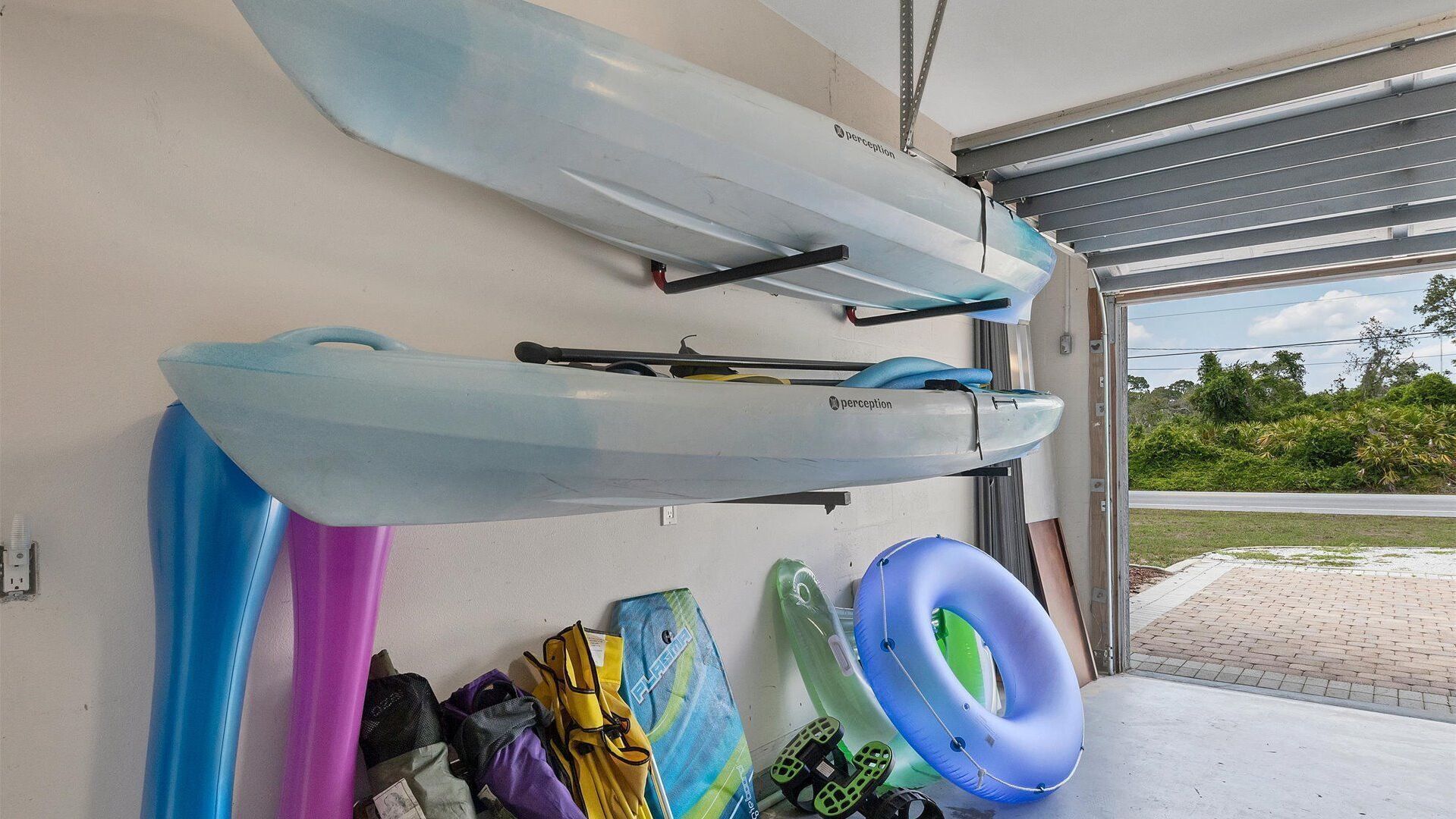 Kayaks and a paddleboard leaning against a wall in a garage.
