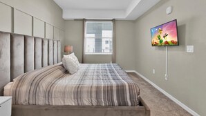 A bedroom with a bed, a TV, a window with blinds, and a ceiling light. - Pxc3151-306 (Kissimmee)