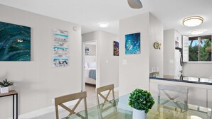 Een moderne eethoek met een glazen tafel, houten stoelen en een potplant.