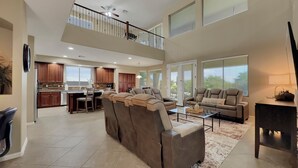 A spacious living area with a large sectional sofa, a dining table, and a kitchen in the background. - Cline Maricopa (Maricopa)