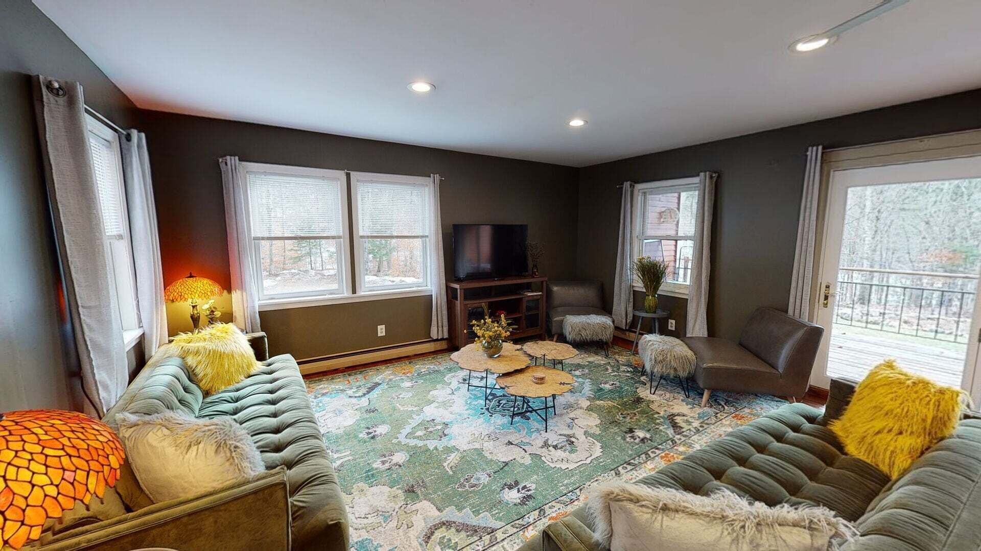 A living room with a sofa set, a television, and a patterned rug.