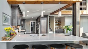 Una cocina moderna con una isla grande, taburetes de bar e iluminación colgante.
