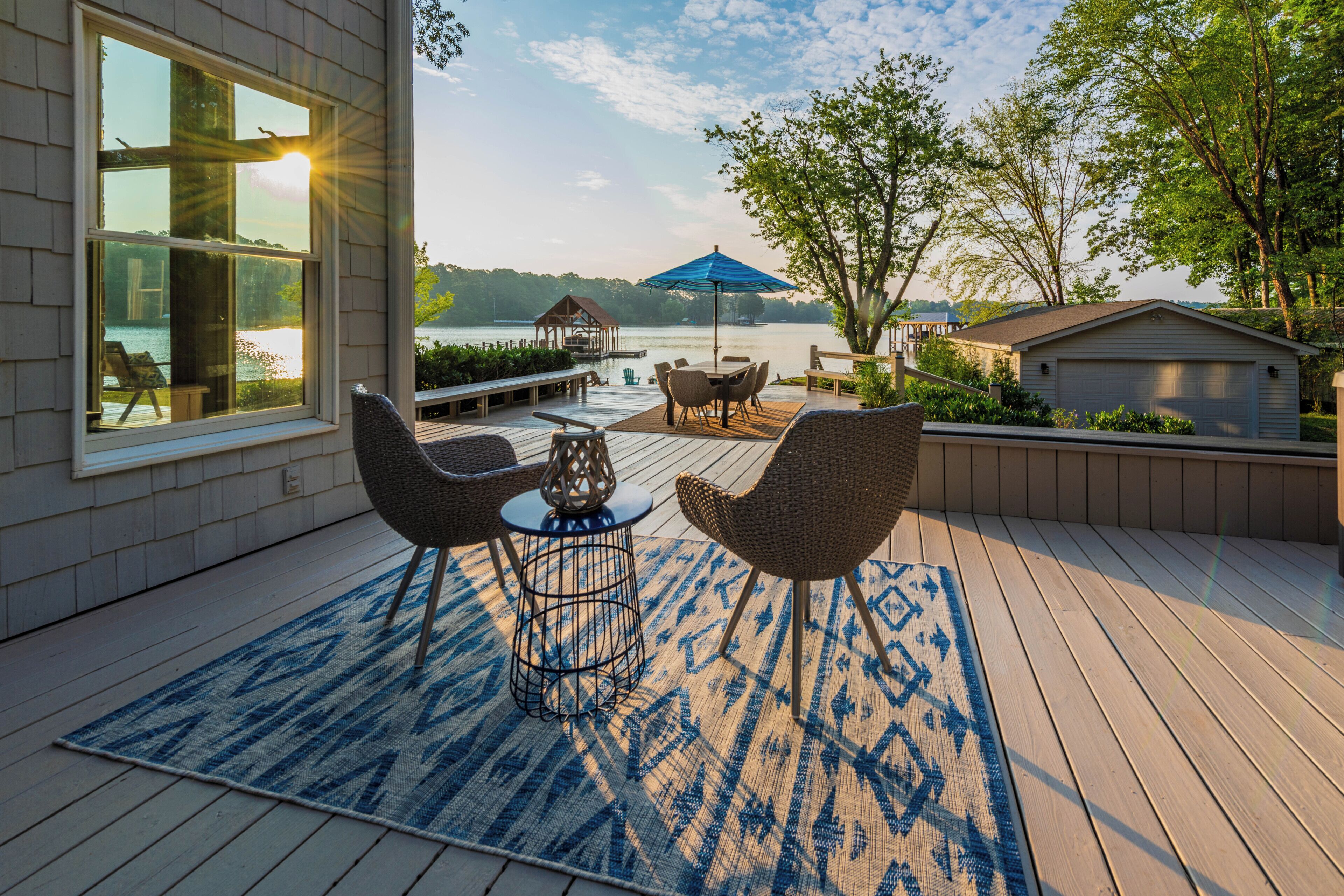 Una terraza con mobiliario exterior, vista a un lago y un pabellón.