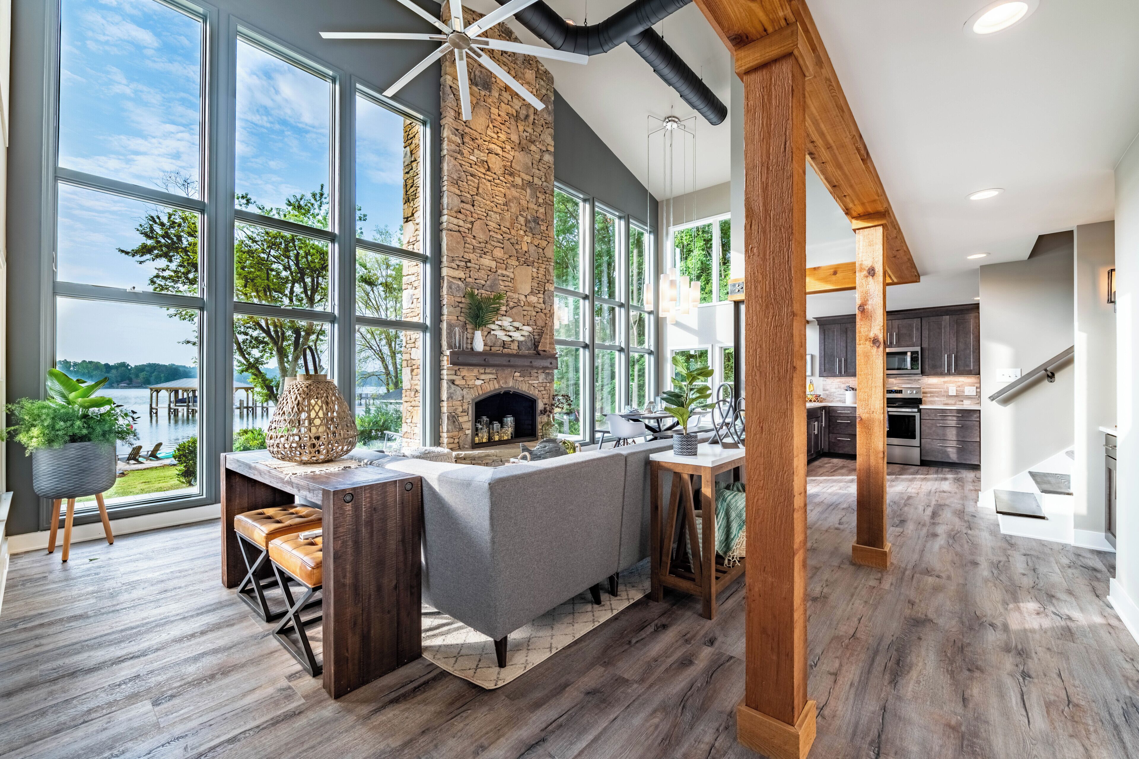 A modern kitchen with large windows, a stone fireplace, and a wooden ceiling.