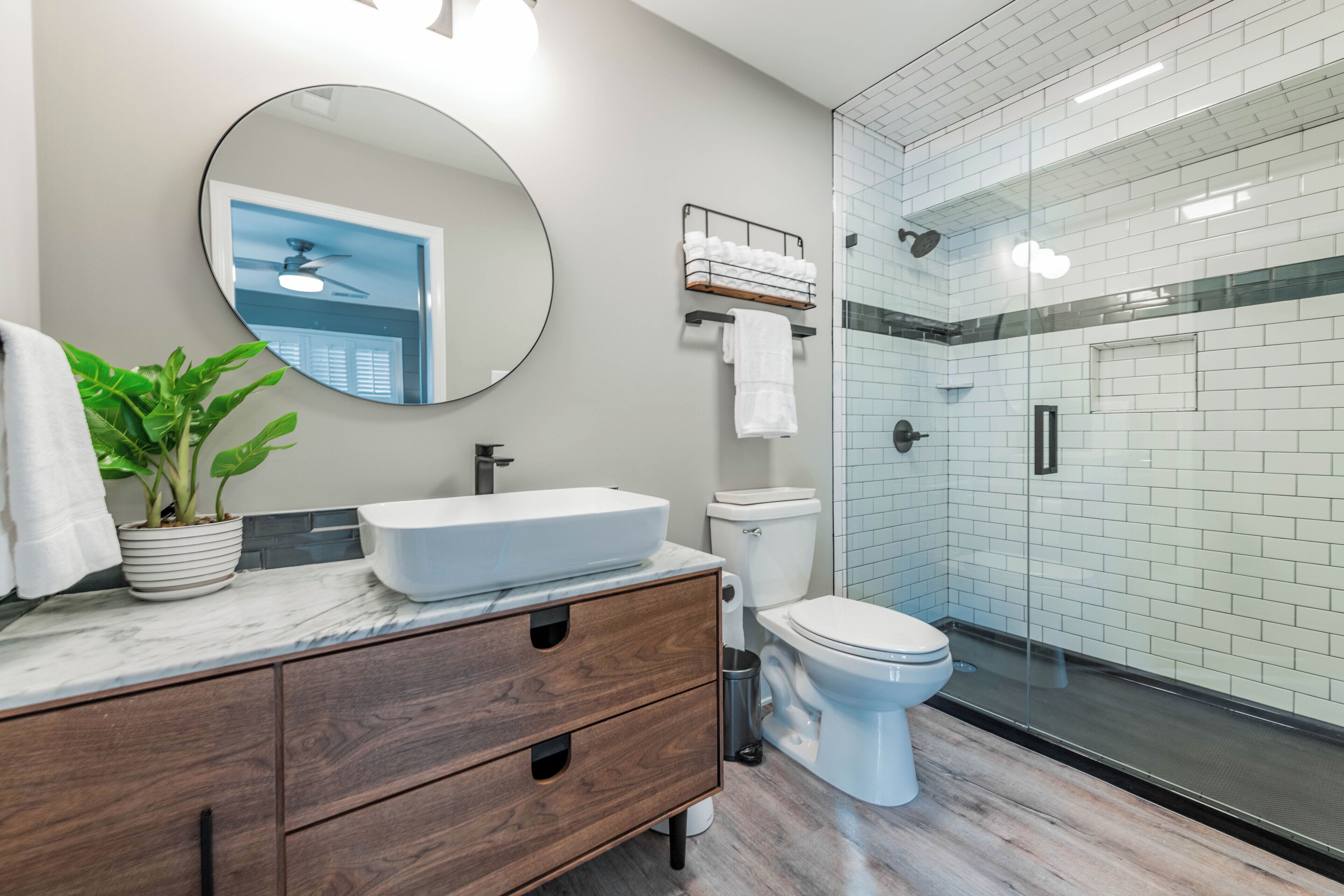Une salle de bain moderne avec un grand miroir, un lavabo, des toilettes et un espace douche.