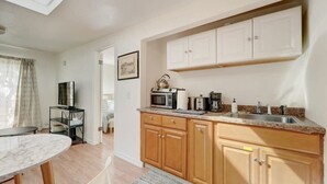 Een kleine keuken met houten kastjes, een magnetron, een koffiezetapparaat en een spoelbak.
