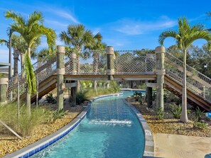 A pool area with a water slide, palm trees, and a wooden bridge. - Nrl4543 (Kissimmee)