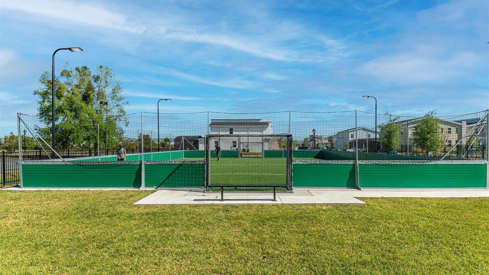 A sports field with a goalpost, surrounded by a fence and trees.