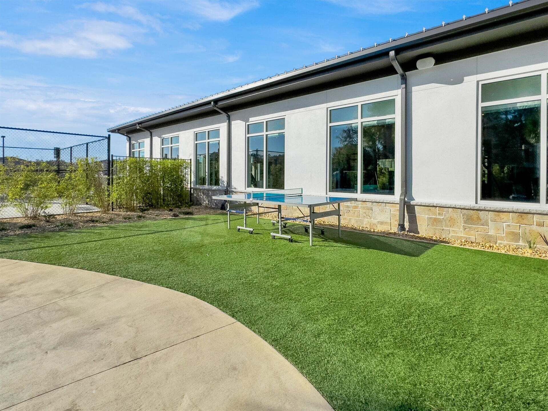 A modern building with large windows, a swimming pool, and a well-maintained lawn.