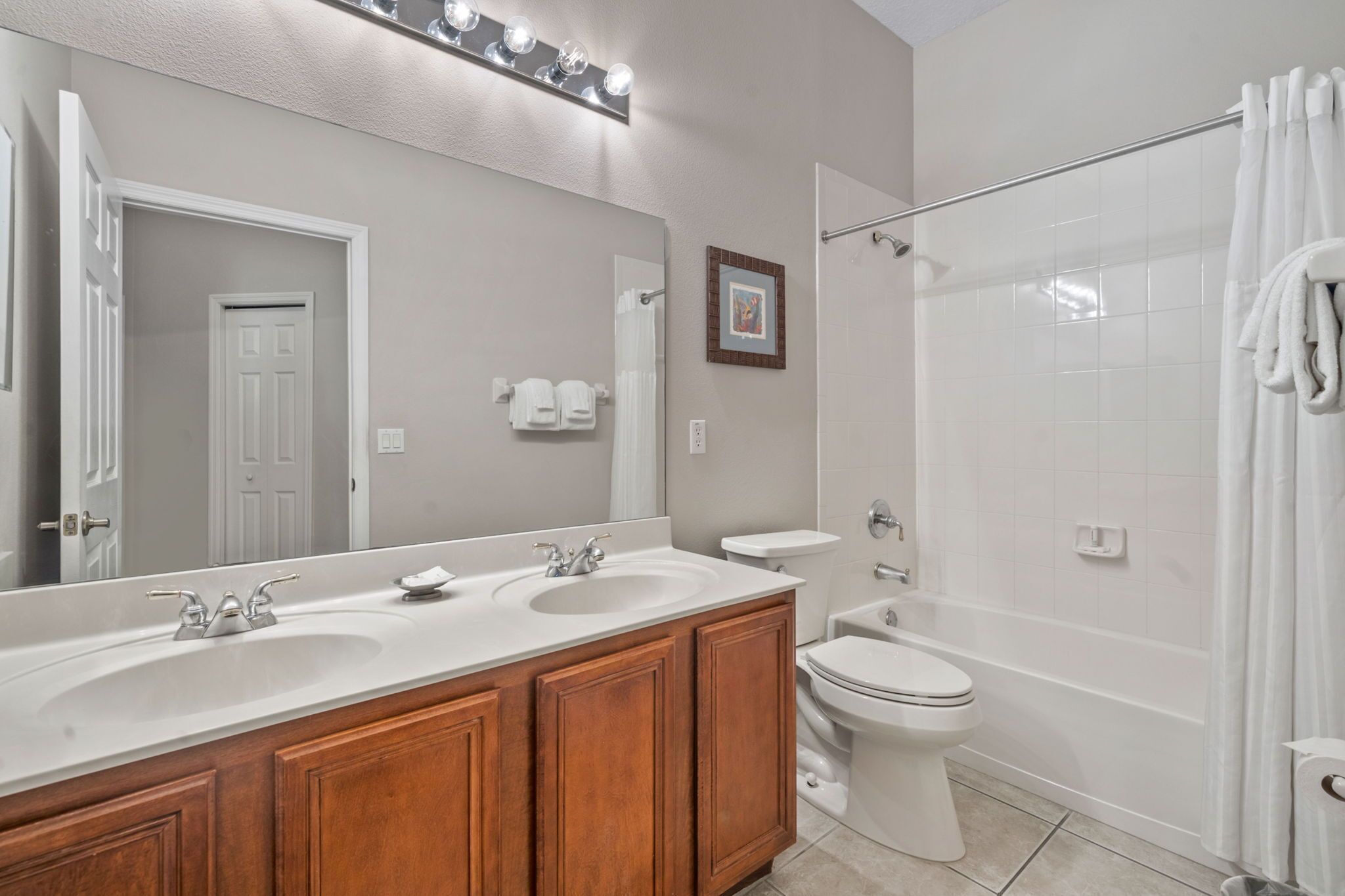 A bathroom with a double sink vanity, a toilet, a bathtub, and a shower.