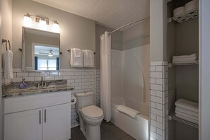 A bathroom with a toilet, sink, mirror, shower, and towel rack. - 941 Pine Manor Family (Marietta)