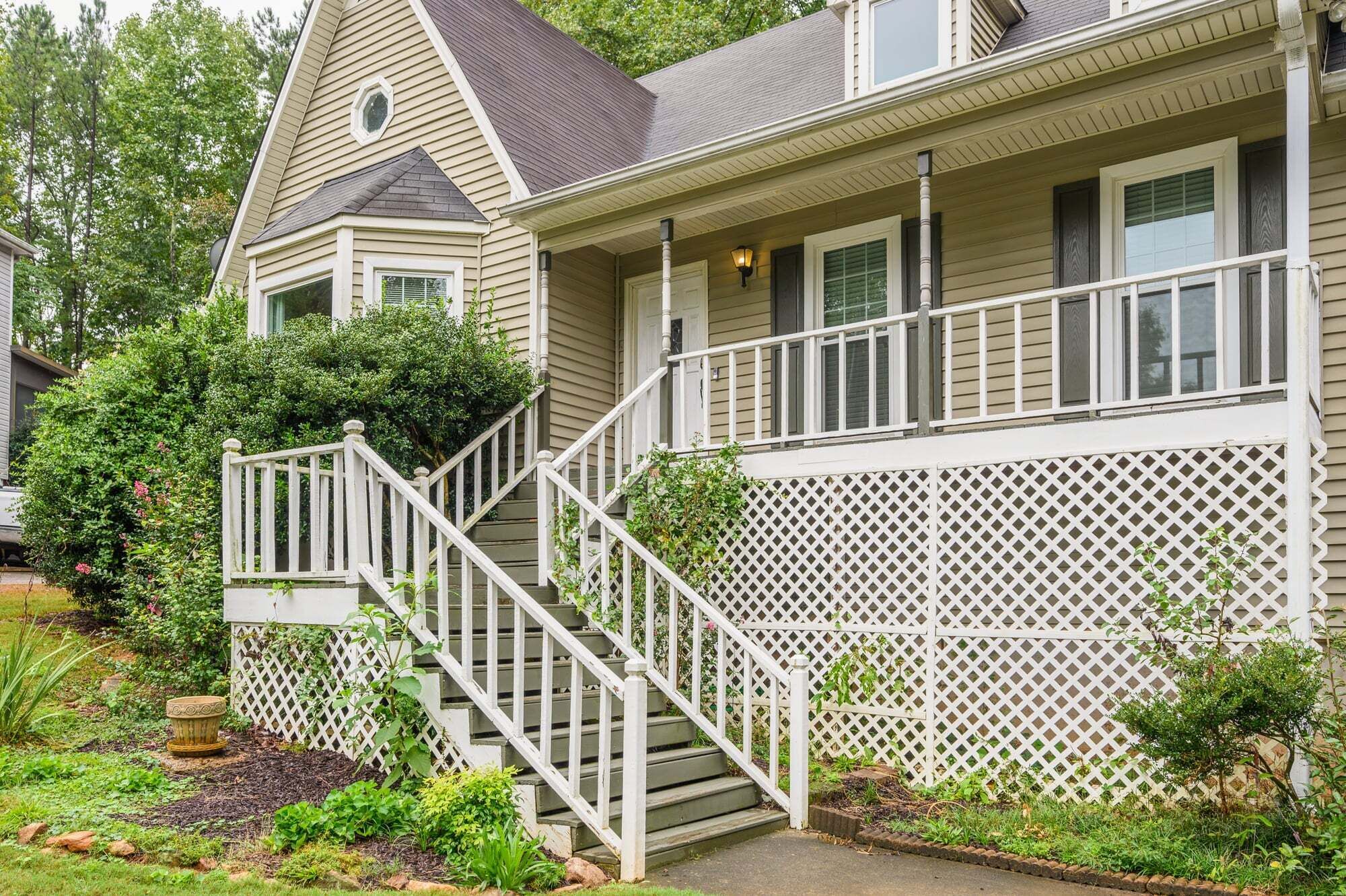 A two-story house with a porch, a staircase, and a garden.