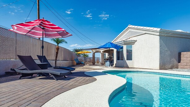 Una piscina con lettini e ombrelloni, una zona relax coperta e un edificio con tetto in tegole.