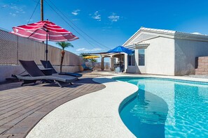 A swimming pool with lounge chairs and umbrellas, a covered seating area, and a building with a tiled roof. - Talley it up to a Great Time in Havasu! (Lake Havasu City)