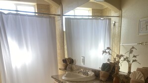 Une salle de bain avec un comptoir en granit, des meubles en bois, un lavabo et des toilettes.