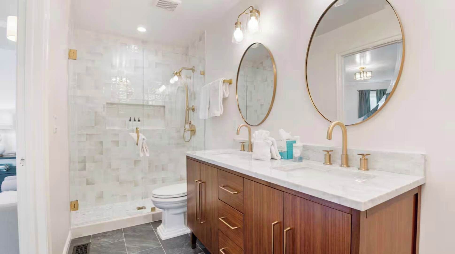 A modern bathroom with a vanity, two mirrors, a shower, and a toilet.