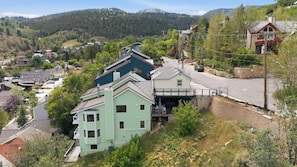 A multi-story building with a green facade, a balcony, and a garage. - Ridge Home | Ski-in, Ski-out (Park City)